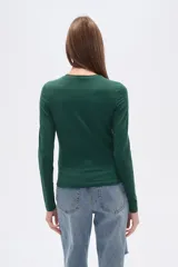 Remera verde esmeralda de manga larga, corte ajustado y cuello redondo.