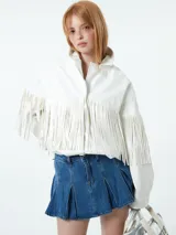 Chaqueta blanca de cuero sintético con cuello camisero, cierre frontal con botones a presión y detalle de flecos en el pecho y las mangas.