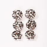 Aros colgantes plateados con tres discos texturizados.