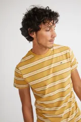 Remera de hombre de manga corta y cuello redondo, con diseño de rayas horizontales en tonos mostaza, blanco y negro. Presenta un ajuste regular y logo pequeño estampado en el pecho.