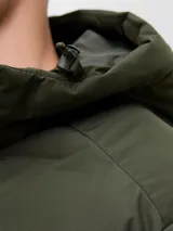 Campera puffer de color verde militar, con capucha integrada, cierre frontal con cremallera y diseño acolchado horizontal. Cuenta con un acabado resistente al agua y puños internos para mayor protección contra el frío.
