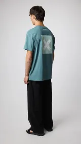 Camiseta color azul verdoso con estampa en la espalda que incluye un cuadrado claro y una letra "X".