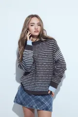 Sweater de tejido de punto con diseño de rayas horizontales en tonos bordó y celeste. Presenta cuello redondo, corte holgado y mangas largas con puños ajustados.