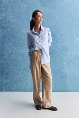 Pantalón de corte recto y holgado, color marrón, con costuras frontales verticales que estilizan la silueta.