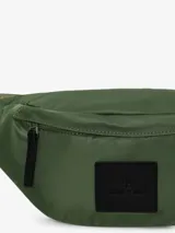 Riñonera urbana Anine Bing modelo Leon, confeccionada en poliamida color verde militar, con cierre de cremallera y parche frontal de piel sintética negra con logo grabado. Incluye correa ajustable.