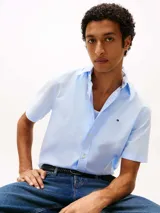 Camisa de manga corta Tommy Hilfiger confeccionada en popelín elástico de algodón BCI color celeste, con cuello abotonado, cierre con botones y logo bordado en el pecho.