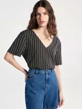 Blusa de cuello en V con estampado geométrico de líneas blancas sobre fondo azul marino.