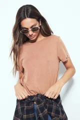 Remera de manga corta color marrón con escote a la base y calce relajado. Las mangas presentan terminación con ojales metálicos.