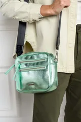 Cartera bandolera rectangular color verde menta metalizado, con tres cierres frontales y correa ancha de tela negra regulable.