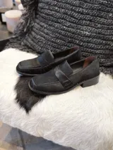 Mocasín de mujer en color negro, confeccionado en cuero con textura de pelo, diseño clásico con banda frontal y suela de taco bajo.