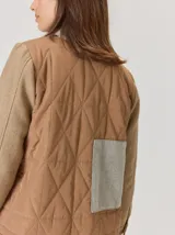 Campera de diseño híbrido con frente acolchado en color tostado, solapas y cuello en tejido de lana con patrón de cuadros tipo príncipe de gales, y mangas en paño de lana color azul marino. Cuenta con cierre frontal de botones.