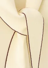 Top amarillo claro de punto con cuello alto y detalle de bufanda integrada con ribetes en contraste.