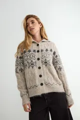Saco de punto con cuello tipo polo, cierre frontal de botones oscuros y diseño de estampado jacquard en tonos grises y beige. Presenta mangas largas con puños acanalados y textura suave.