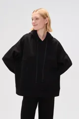 Canguro negro holgado con capucha y cordones ajustables, mangas largas y bolsillos laterales.