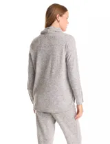 Buzo de tejido suave con cuello volcado ajustable mediante cordones con punteras metálicas. Presenta mangas largas con puños decorados con botones metálicos, hombros caídos y ruedo redondeado con aberturas laterales.