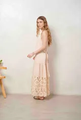 Vestido largo beige con cuello halter y detalle de broderie calado en el dobladillo inferior.