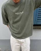 Remera oversize negra con diseño gráfico en la espalda que incluye la inscripción "Kaboa Radio" y un personaje ilustrado, de corte amplio y mangas cortas.
