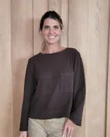 Remera de manga larga color marrón chocolate, con cuello redondo y dos bolsillos frontales tipo parche.