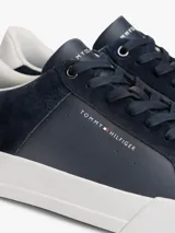 Zapatillas de tenis Tommy Hilfiger de corte bajo, confeccionadas en una combinación de piel nobuk y piel lisa en color azul marino. Presentan suela de goma blanca, cordones al tono y detalle de panel blanco en el talón con el logo de la marca.