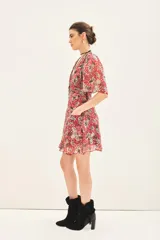 Vestido corto con estampado floral en tonos rojo/fucsia y gris/azul, escote en V, mangas cortas con vuelo y frunces en el delantero y espalda. Posee bolsillos delanteros.