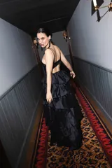 Vestido largo negro de tafeta con leve brillo, escote recto, breteles finos y falda de múltiples capas de volados con gran volumen.