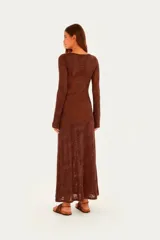 Vestido largo de punto color marrón, con diseño estampado de hojas en tono sutil, cuello redondo, mangas largas acampanadas y corte recto hasta los tobillos.