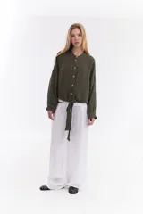 Camisa blanca de lino italiano, de corte holgado, mangas largas abullonadas, cuello mao y cierre frontal con botones, con diseño para anudar en la cintura.