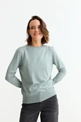 Sweater de punto liso color marrón topo, con cuello redondo y manga larga. Presenta un detalle de tres botones pequeños en la abertura del puño.