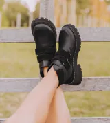 Bota corta de cuero vacuno color negro, con suela de caucho tipo tractor y cierre mediante doble tira de velcro en el empeine.