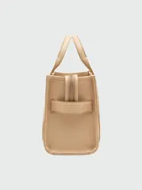 Cartera tipo tote de Marc Jacobs, confeccionada en cuero granulado color azul marino. Presenta el logo de la marca estampado en el frente, doble asa superior y correa ajustable y extraíble para llevar al hombro o cruzada.