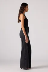 Pantalón de jean acampanado negro de tiro alto con dos botones a la vista.