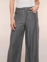 Pantalón wide leg de denim liviano gris, con tiro alto, presillas para cinturón, bolsillos laterales y corte recto de piernas anchas.