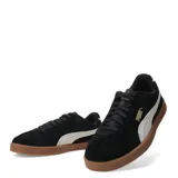 Championes Puma modelo Club II Era Suede, de diseño urbano con exterior de gamuza negra, franja lateral característica en color blanco y suela de goma color caramelo.