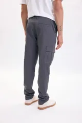 Pantalón cargo de color gris oscuro, con múltiples bolsillos laterales en las piernas y corte clásico.