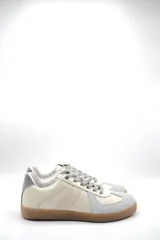 Zapatillas urbanas de cuero color crema con puntera y talón en gamuza gris, suela de goma marrón y cordones grises.