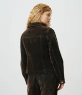Campera ajustada de jean con acabado aterciopelado color marrón oscuro, cuello camisero, manga larga, cierre frontal con botones metálicos y bolsillos frontales con solapa.