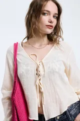 Camisa de algodón color crudo, de manga larga y corte fluido, con escote en V y cierre frontal mediante lazos.