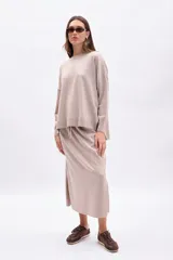 Buzo de tejido de punto color beige con hilo de lurex que le da un brillo sutil. Presenta cuello redondo, mangas largas y un calce holgado.