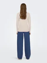 Suéter de punto fino color beige claro (eggnog melange), con cuello redondo y mangas largas terminadas en puños con detalle de botones.