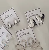 Aros tipo caravana con diseño de corazón inflado en acabado plateado brillante.