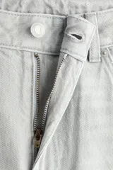 Pantalón de jean color gris claro, de tiro alto y diseño baggy con corte holgado en la cadera y piernas anchas estilo balloon.