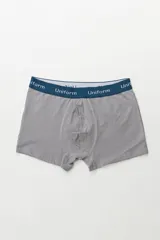 Boxer de algodón color gris, con pretina elástica azul marino que lleva la palabra "Uniform" repetida en blanco.
