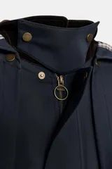 Trench azul marino con cuello de pana marrón y capucha desmontable con interior a cuadros. Tiene charreteras, canesú, bolsillos con solapa y cierre frontal con cremallera y botones a presión ocultos.