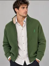 Campera de tejido color verde con cierre frontal completo, cuello alto y bordado sutil en el pecho.