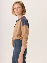 Buzo de manga larga con diseño color block. Cuerpo principal color camel, sección central de la espalda color azul marino liso y hombros con tejido de lana texturado en tonos azules. Posee un parche de cuero marrón con el logo grabado en la espalda.