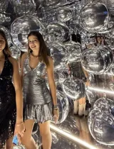 Vestido corto negro con estampado de plumas doradas, escote en V, breteles finos cruzados en la espalda, cut-outs laterales y volado en el ruedo.