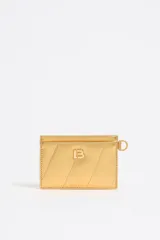 Tarjetero dorado con diseño acolchado y logo metálico en el frente.