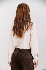 Camisa color crudo de cuello alto con botones y frunces en los puños y el cuello.