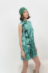 Vestido corto sin mangas con estampado de flores turquesas y amarillas, corte cheongsam con ribete negro y lazos negros.