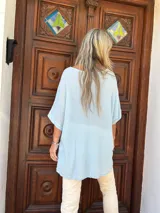 Blusa de textura arrugada en color celeste, con cuello redondo, mangas cortas amplias y corte holgado.